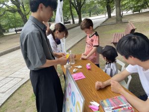 外国のお子様と一緒に折り鶴を折る様子（市大生チャレンジ事業）